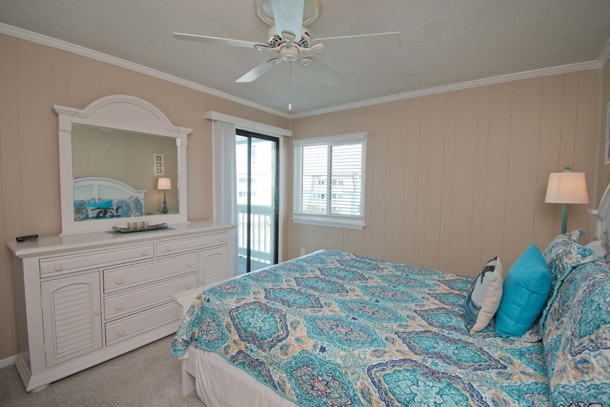 A bedroom with a bed, dresser, and a ceiling fan.