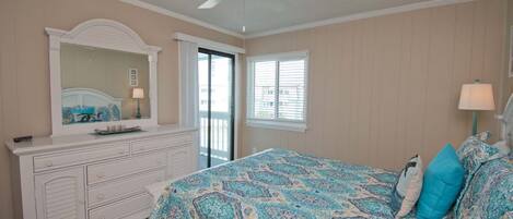 A bedroom with a bed, dresser, and a ceiling fan.