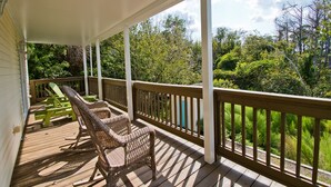 A wooden deck with wicker chairs and a table, overlooking a lush green landscape. - Shangri La, Oceanside House in Emerald Isle, NC! (Emerald Isle)