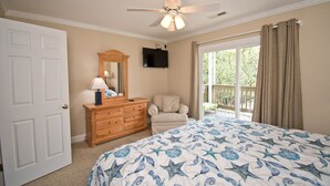 A bedroom with a bed, dresser, chair, ceiling fan, and a window with curtains. - Shangri La, Oceanside House in Emerald Isle, NC! (Emerald Isle)