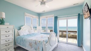 A bedroom with a bed, dresser, and a view of the beach.