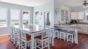 A spacious kitchen with a large island, white cabinetry, and a view of the beach.