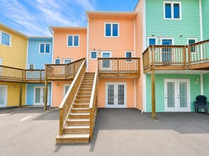A multi-story building with a central staircase, multiple windows, and a wooden balcony.