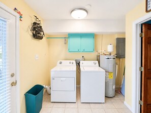 Ein Waschraum mit zwei Frontlader-Waschmaschinen, einem blauen Schrank und einem Warmwasserbereiter.