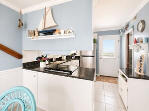 A kitchen with white cabinets, a black countertop, and a sailboat decoration.