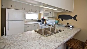 A compact kitchen with white cabinets, a stainless steel sink, a microwave, and a stove. - Sound Of The Sea North 205, Oceanview Condo in Emerald Isle, NC! (Emerald Isle)
