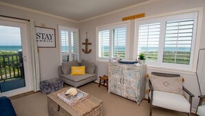 A cozy living room with a grey sofa, a small table, and a cabinet with a view of the ocean. - Southwinds F7, Oceanfront Condo in Atlantic Beach, NC! (Atlantic Beach)