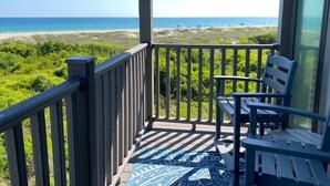 A balcony with a view of the beach, a chair, and a patterned rug. - Southwinds F7, Oceanfront Condo in Atlantic Beach, NC! (Atlantic Beach)