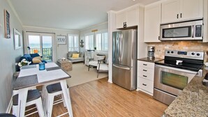 A modern kitchen with stainless steel appliances, a dining area with a table and chairs, and a view of the ocean through large windows. - Southwinds F7, Oceanfront Condo in Atlantic Beach, NC! (Atlantic Beach)