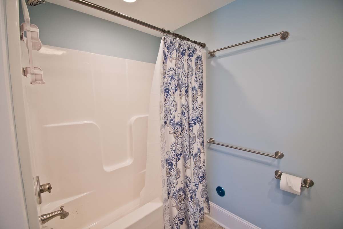 A bathroom with a walk-in shower, a white bathtub, and a blue wall.
