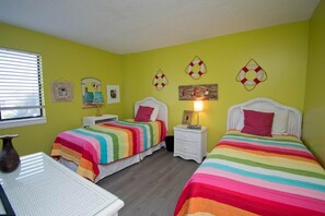 A room with two beds, a small table, and a window. - Summer Winds A-115, Oceanfront Condo in Indian Beach, NC! (Indian Beach)