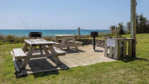 Zona de picnic con mesas y bancos de madera, un bote de basura y un letrero que indica que no se permite arrojar basura.