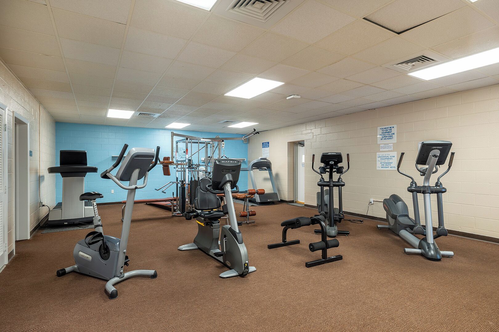 Une salle de sport équipée de tapis de course, de vélos elliptiques et d’appareils de musculation.