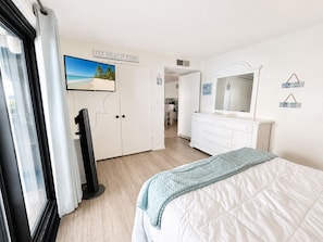 Un dormitorio con cama, televisor, cómoda y espejo.