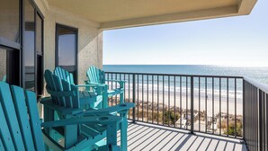 A balcony with turquoise Adirondack chairs, a view of the beach, and a clear sky. - Summer Winds B-331, Oceanfront Condo in Indian Beach, NC! (Indian Beach)