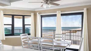 A room with a table and chairs, large windows with ocean views, and a ceiling fan. - Summer Winds B-331, Oceanfront Condo in Indian Beach, NC! (Indian Beach)