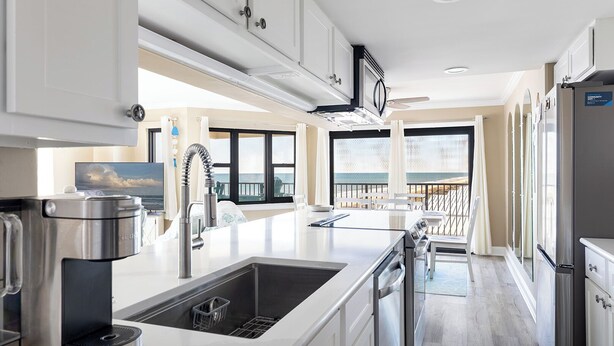 A modern kitchen with a large island, stainless steel appliances, and a view of the ocean. - Summer Winds B-331, Oceanfront Condo in Indian Beach, NC! (Indian Beach)