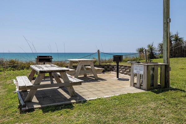 A picnic area with wooden tables and benches, a trash can, and a sign indicating no trash allowed.