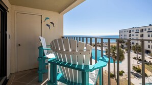 A balcony with two Adirondack chairs, a door, and a view of the ocean and buildings. - Summer Winds A-415, Oceanfront Condo in Indian Beach, NC! (Indian Beach)