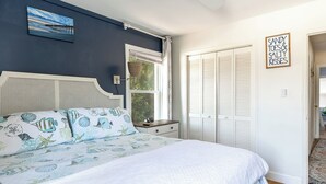Une chambre à coucher avec un lit, une table de chevet, une fenêtre et un placard.
