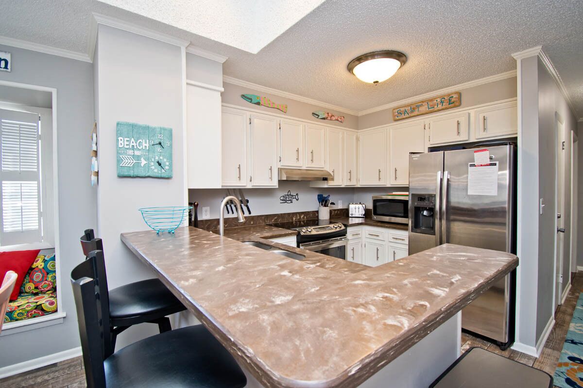 A kitchen with white cabinets, a stainless steel refrigerator, and a granite countertop.