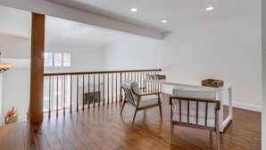 A spacious room with wooden flooring, a white railing, and a seating area with two chairs. - Your Spring & Summer Coastal Retreat Awaits in Huntington Beach!  (Huntington Beach)