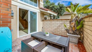 A patio with wicker furniture, a table, and a potted plant. - Your Spring & Summer Coastal Retreat Awaits in Huntington Beach!  (Huntington Beach)