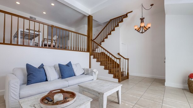 A living room with a staircase, a white sofa with blue cushions, a white coffee table, and a chandelier. - Your Spring & Summer Coastal Retreat Awaits in Huntington Beach!  (Huntington Beach)
