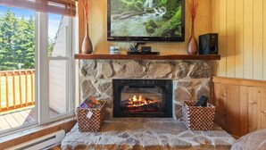 A stone fireplace with a TV above it, a wooden mantel, and two baskets on either side.