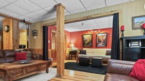 A cozy living room with a wooden coffee table, leather sofas, and a fireplace.