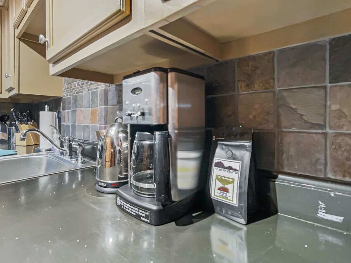 Een keuken met een koffiezetapparaat, een glazen kan en een koffiepadapparaat.