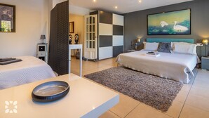 A modern bedroom with a large bed, a smaller bed, and a desk with a bowl. - Villa Pacifica by Abahana Villas (Javea / Xàbia)