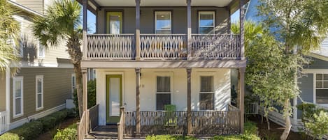 A two-story building with a balcony, a front door, and a small porch area.
