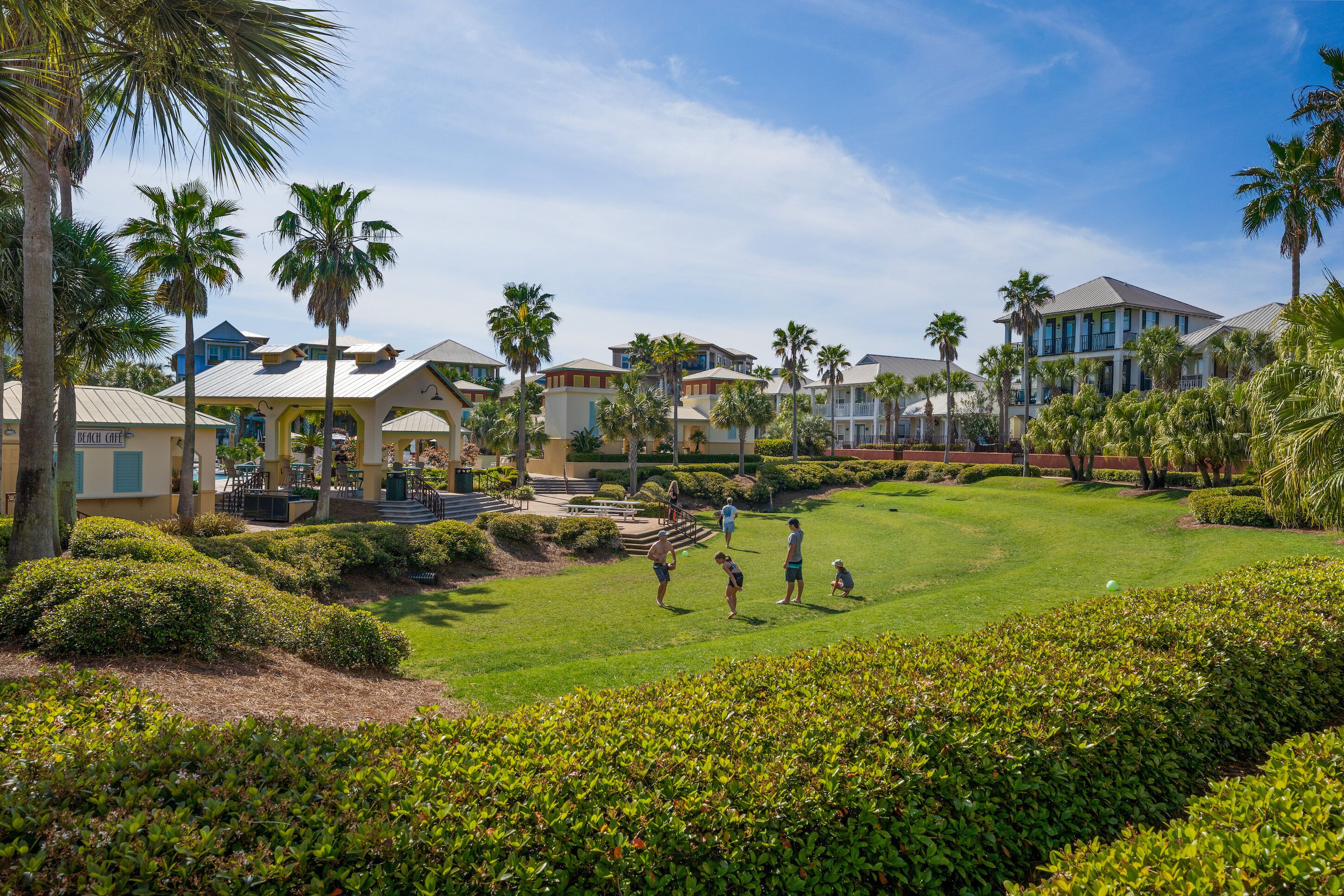 A golf course with a clubhouse, palm trees, and a well-maintained lawn.