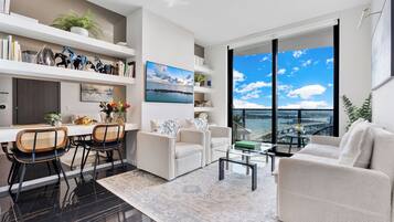 A modern living room with a dining area, large windows with a view, and a balcony.