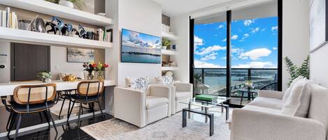 En moderne stue med spiseplads, store vinduer med udsigt og en balkon.