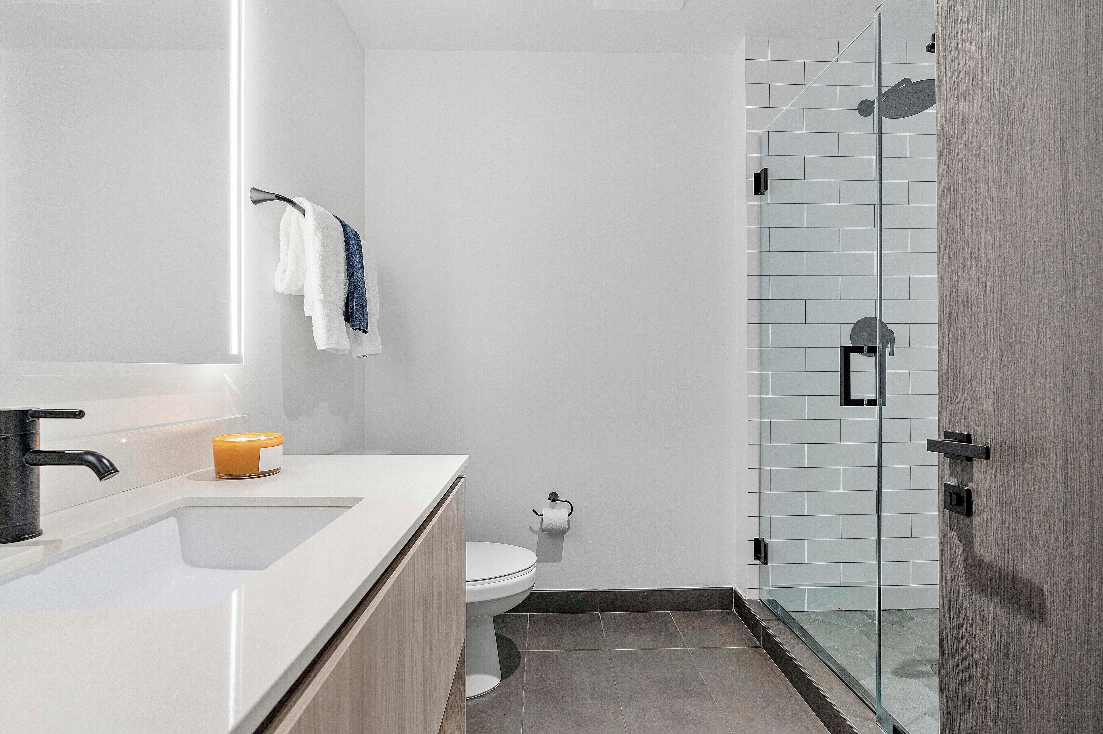 Un baño moderno con un lavamanos blanco, inodoro y cabina de ducha de vidrio.
