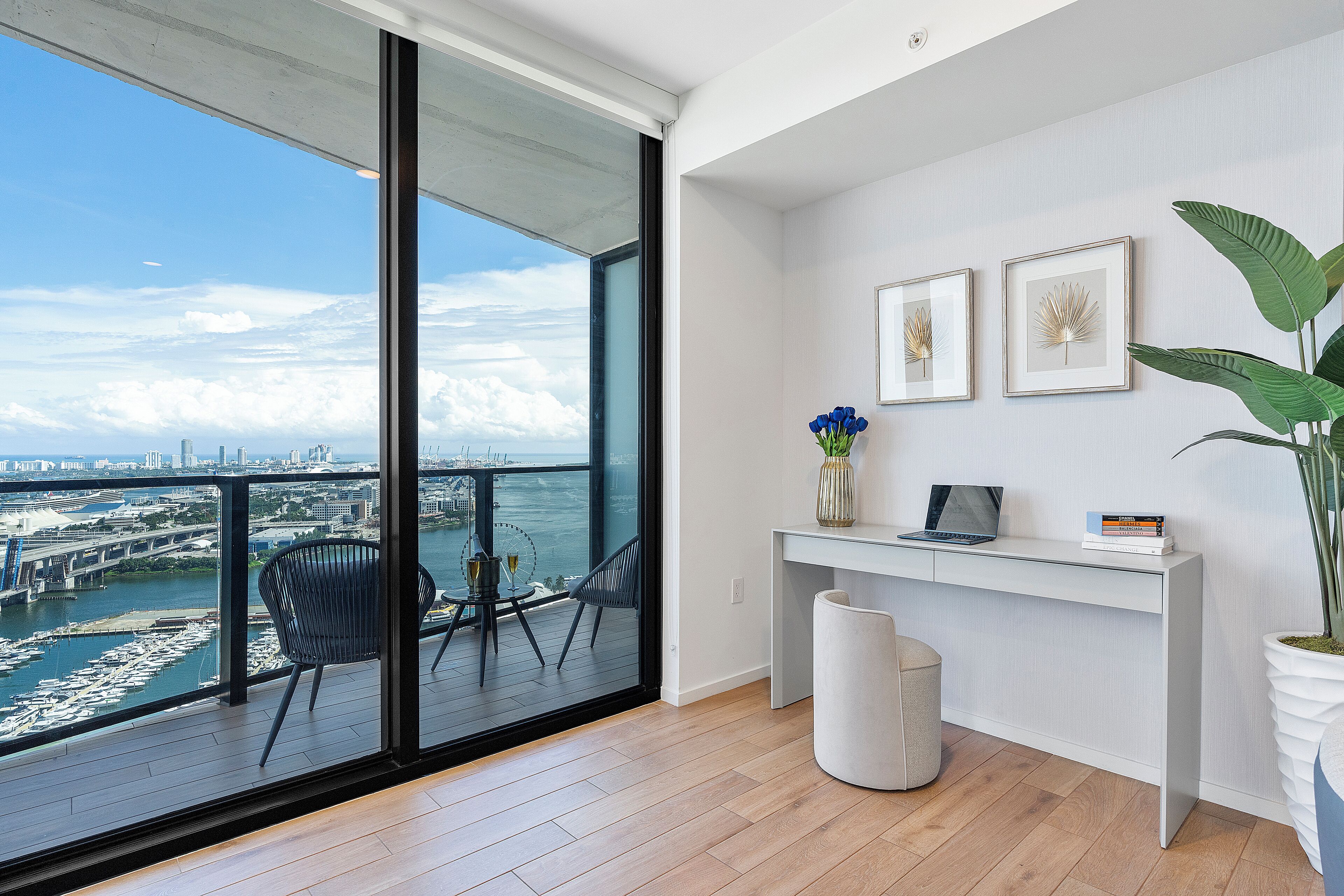 Una habitación moderna con un ventanal grande con vistas a un puerto deportivo y al horizonte de la ciudad.
