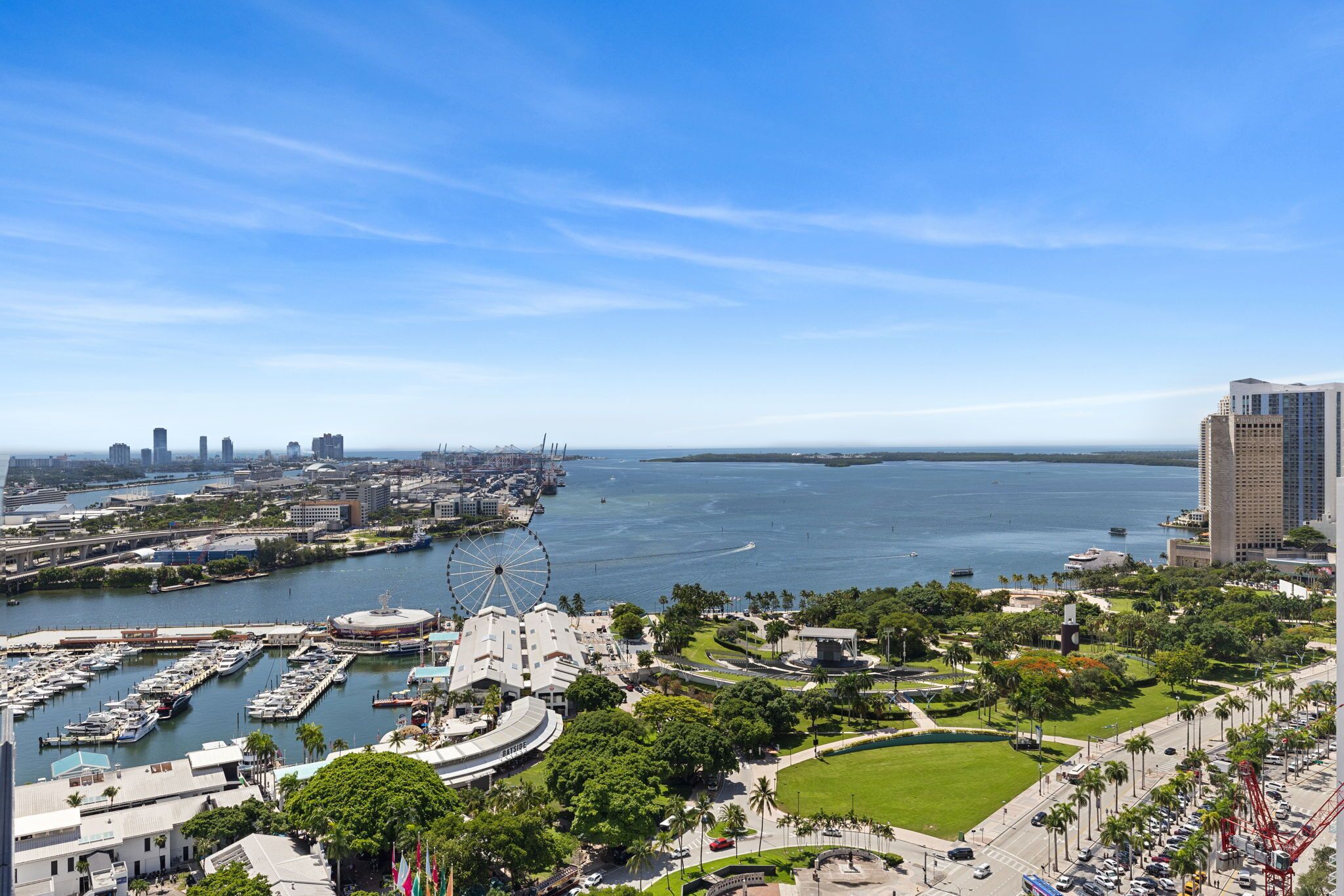 A coastal cityscape with a marina, a large Ferris wheel, and a prominent building with a dome.