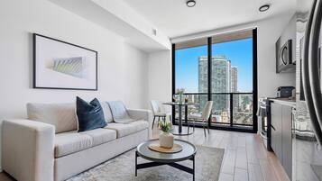 A modern living room with a sofa, a coffee table, and a city view through large windows.