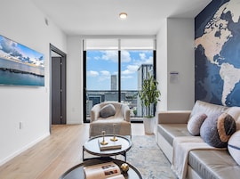 A modern living room with a large window, a world map, and a view of the cityscape.