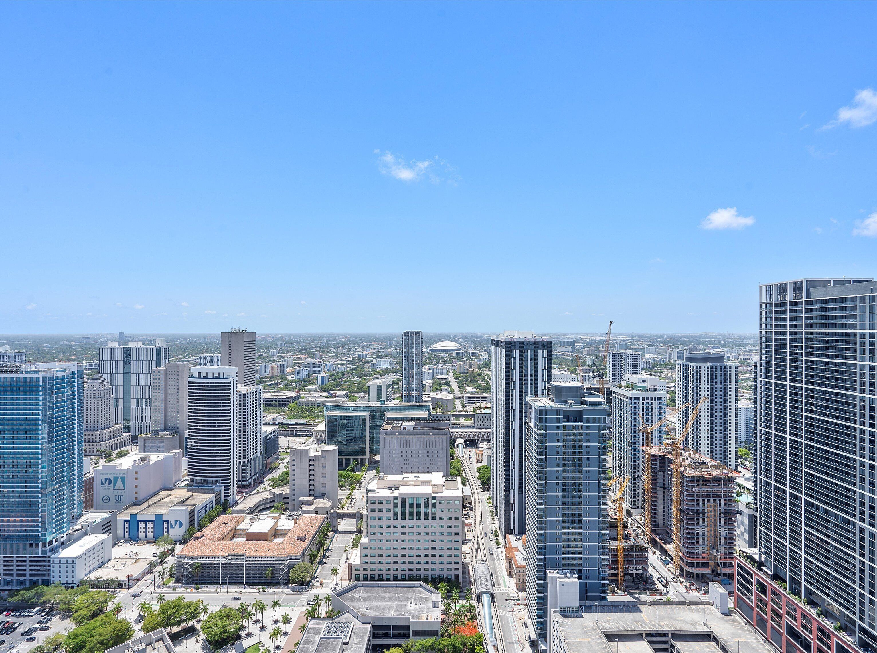 A cityscape with high-rise buildings, including a mix of modern and older architecture, under a clear blue sky.