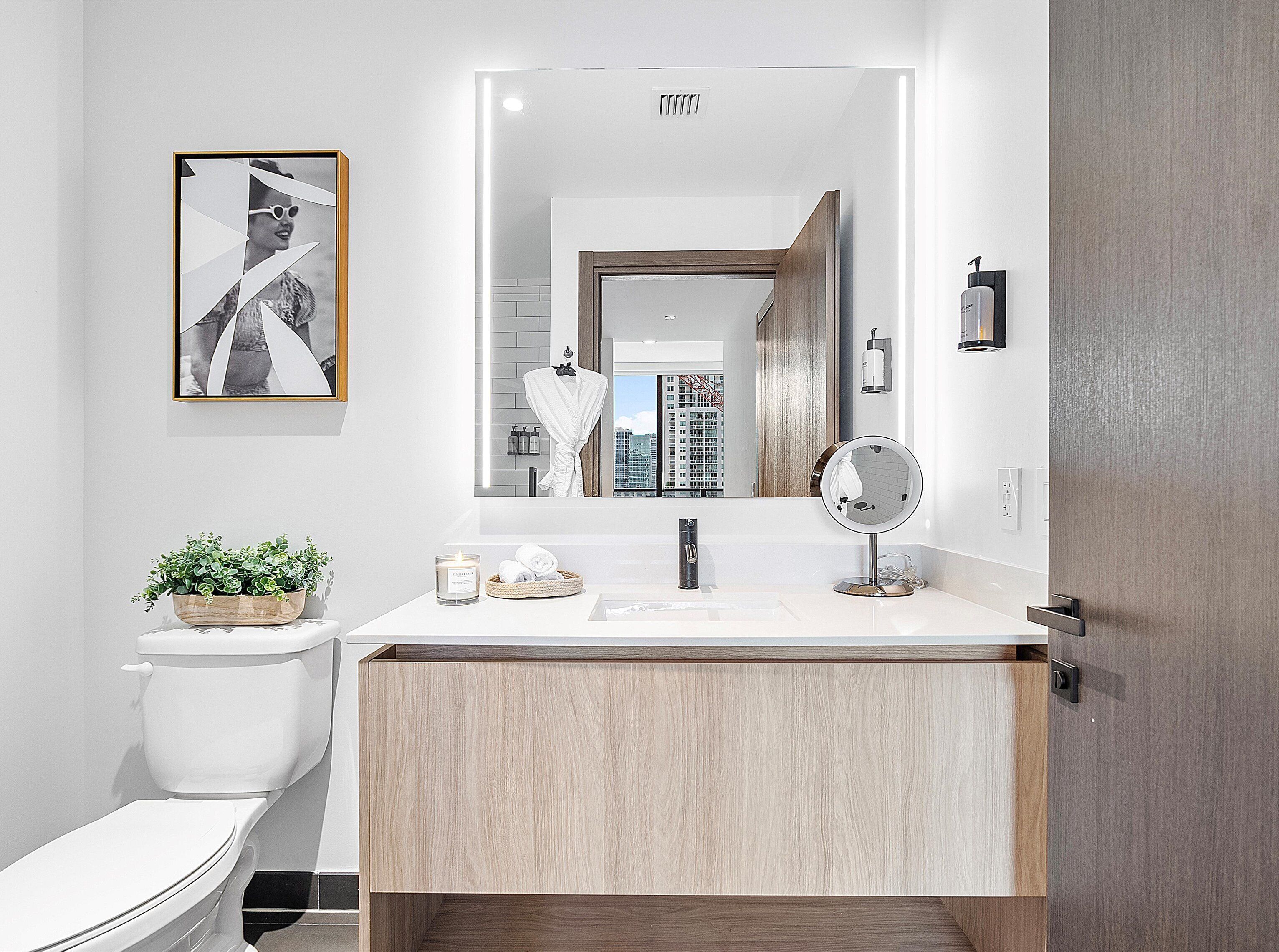 A modern bathroom with a toilet, sink, and mirror.