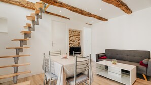 Een modern interieur met een trap, een eettafel, stoelen, een bank en een open haard.