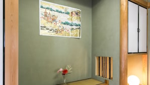 Una habitación japonesa tradicional con suelo de tatami, un panel shoji y un pergamino colgado.