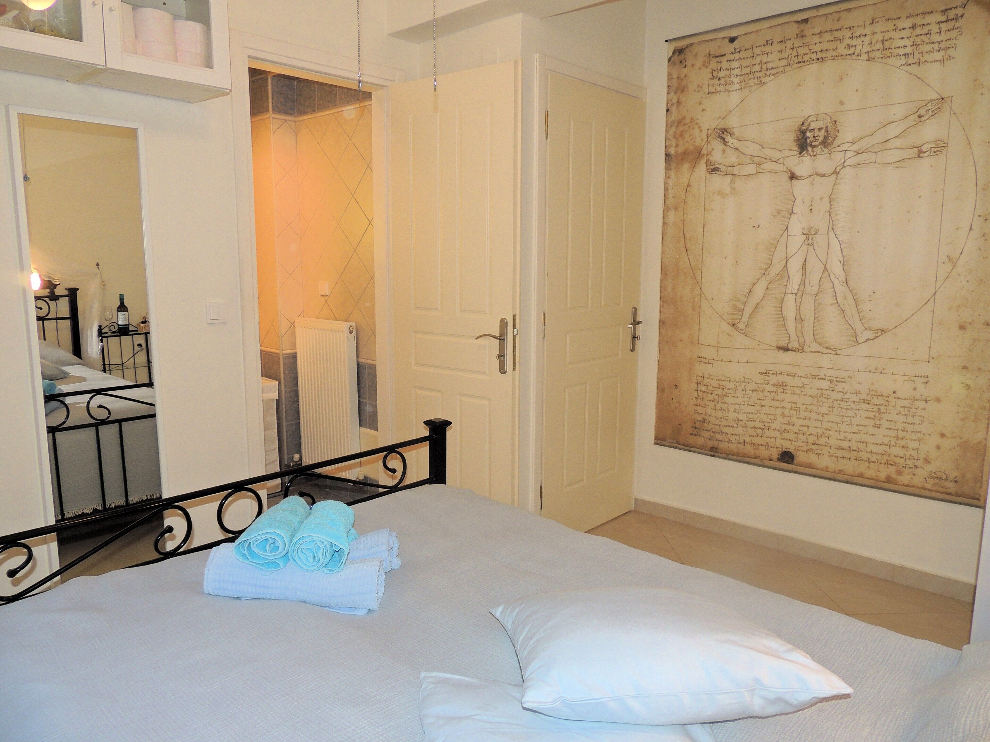 Una camera da letto con un letto, uno specchio grande, una porta e una parete con un disegno storico.