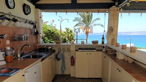 A kitchen with a view of the sea, a clock, and hanging light bulbs. - 4 Bedrooms, perfect sea views, Infinity pool, Hot tub, Walk to beach & tavernas. (Chania)