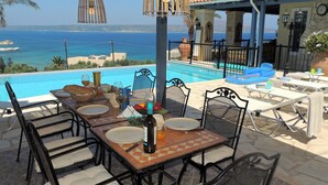 A dining area with a view of the sea, a pool, and outdoor seating. - 4 Bedrooms, perfect sea views, Infinity pool, Hot tub, Walk to beach & tavernas. (Chania)