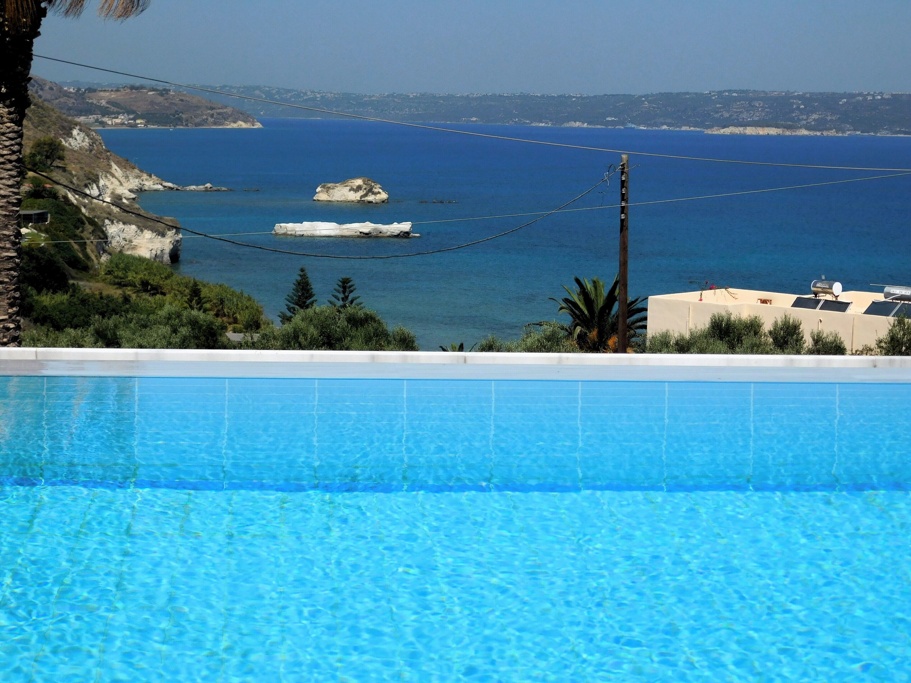 Ein Swimmingpool mit Blick auf das Meer und eine felsige Küste.