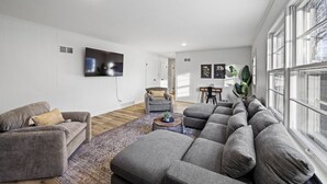 Una sala moderna con un sofá seccional, un sillón gris y una mesa de centro.